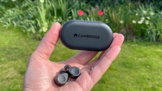 Cambridge Audio Melomania M100 in hand with charging case in background