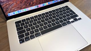 The 2024 MacBook Air M3 on a wooden table in front of a bookshelf.