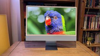 The 2023 M3 iMac on a wooden desk, showing the features of macOS Sonoma