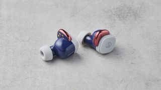 A pair of Audio-Technica ATH-SQ1TW wireless earbuds, sitting on a marble slab