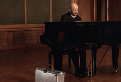 Nils Frahm at the piano with a Rimowa Hammerschlag case beside him