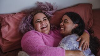 Two women with bigger builds cuddle up together comfortably on a supportive mattress