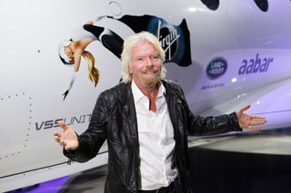 Richard Branson stands in front of VSS Unity, smiling.