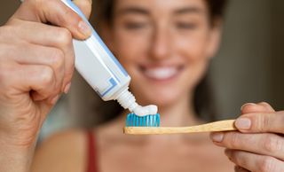 woman putting toothpaste on tooth brush