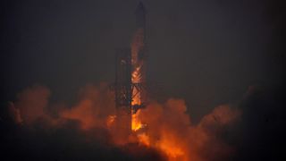 a large silver rocket flies through a blue sky above a column of flame