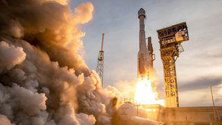 a rocket lifting off from a launch pad beside a huge plume of steam