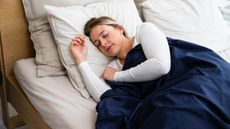 A woman sleeping on a mattress under a blue duvet