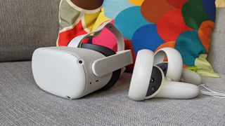 Oculus Quest 2 og kontrollere på en grå sofa.