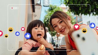 Mother and daughter doing livestream via social media on smartphone and receiving comments and likes.