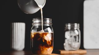Pouring milk into glass jar for frappe coffee