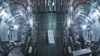 view inside fusion reactor, covered in grey paneling and bright lights.