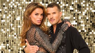 From left to right: Brooks Nader holding Gleb Savchenko, and his arm is around her for Dancing With The Stars portrait. 