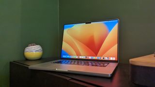 MacBook Pro 16-inch (2023) on wooden desk with green background