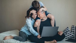 Family looking down at laptop while embracing