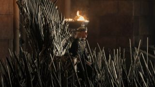 Tom Glynn-Carney as Aegon sitting on The Iron Throne surrounded by swords in House of the Dragon.