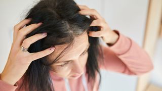 woman inspecting grey heads along her hairline