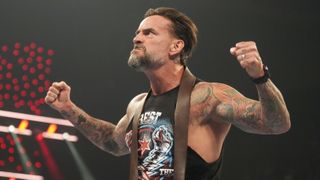 WWE wrestler CM Punk, wearing a black muscle vest, flexes his muscles to the crowd ahead of WWE Bad Blood 2024 live stream