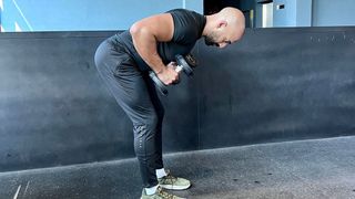 a photo of trainer Ali Malik performing a dumbbell tricep kickback