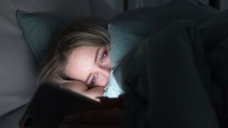 A phone being used by a woman in bed