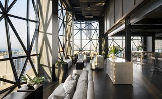 Lounging area of the restaurant with grey sofa, cushions and black tables. Marble designed center piece