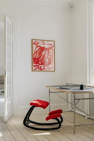 A home office kneeling chair. Black legs with a red fabric.