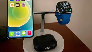 Belkin BoostCharge Pro 3-in-1 on a night stand, with AirPods, and iPhone and an Apple Watch