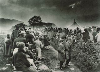 a large crowd of people gathered and looking up at a partially cloudy sky to see the total eclipse of the sun.