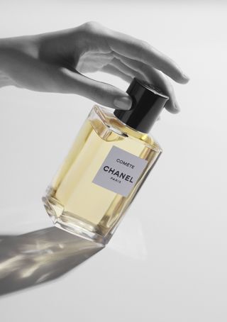 Chanel Comète eau de parfum held between two hands in black and white