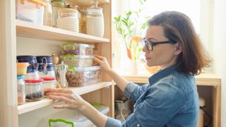 Woman looking through the pantry for things she'll need in the morning