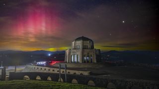 Auroras behind a building on a hill