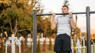 Man performing a chin-up outside