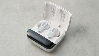 a mixx streambuds mini ultra case rests on the table with its lid open, showing the two earbuds inside