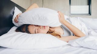 How to sleep with anxiety: a woman holds a pillow while lying in bed worrying