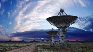 Radio telescopes point skyward at sunset.