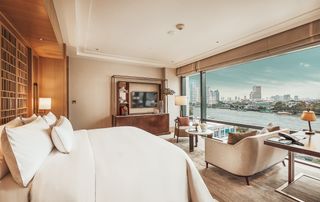 Bedroom in neutral tones with full length windows looking out over the city