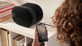 Lifestyle picture of Sonos Era 300 in black being controlled by a woman using the mobile app