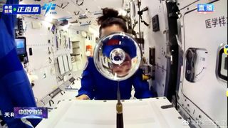 a sphere of water in front of an astronaut on a space station