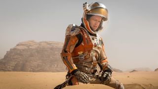 Mark Watney (Matt Damon) in a spacesuit kneeling in the sand on the surface of Mars in "The Martian"