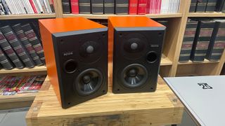 Epos ES-7N standmount speakers on wooden table in front of bookcases