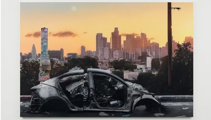 Manipulated photograph of destroyed car against backdrop of city skyline at sunset, from Sayre Gomez ‘Heaven ‘N‘ Earth’ exhibition at Xavier Hufkens