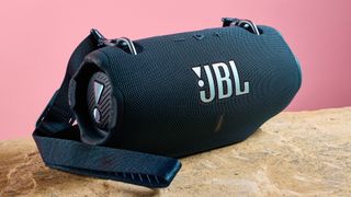 JBL Xtreme 4 kivisellä tasolla pinkkiä seinää vasten