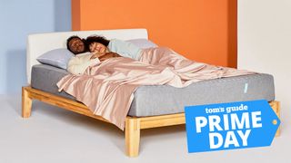 October's Amazon Prime Day mattress deals guide image shows a couple sleeping on a Siena Memory Foam Mattress placed on a wooden bed frame, with a blue Prime Day sales badge overlaid in the bottom right hand corner