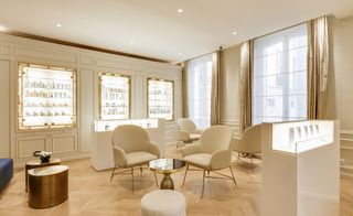 Tables and chairs on a wooden floor in front of illuminated cabinets displaying beauty products