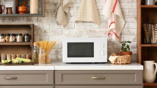 A modern looking microwave on a counter top in a modern kitchen