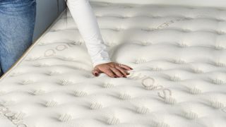 A reviewer places her hand on top of the Saatva Classic mattress during a temperature regulation test