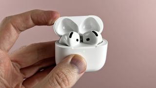 AirPods 4 with the case open, held in a man's hand