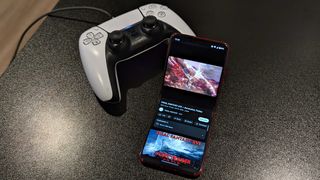 The Razr+ playing a YouTube video next to a DualSense controller