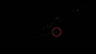 a bright light on earth circled by red, surrounded by darkness, in a picture taken from space