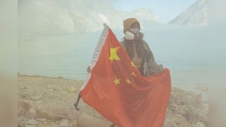 A woman in China holds a Chinese flag wearing a gas mask to help against the smog 