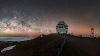 a telescope on a mountaintop under a very starry sky